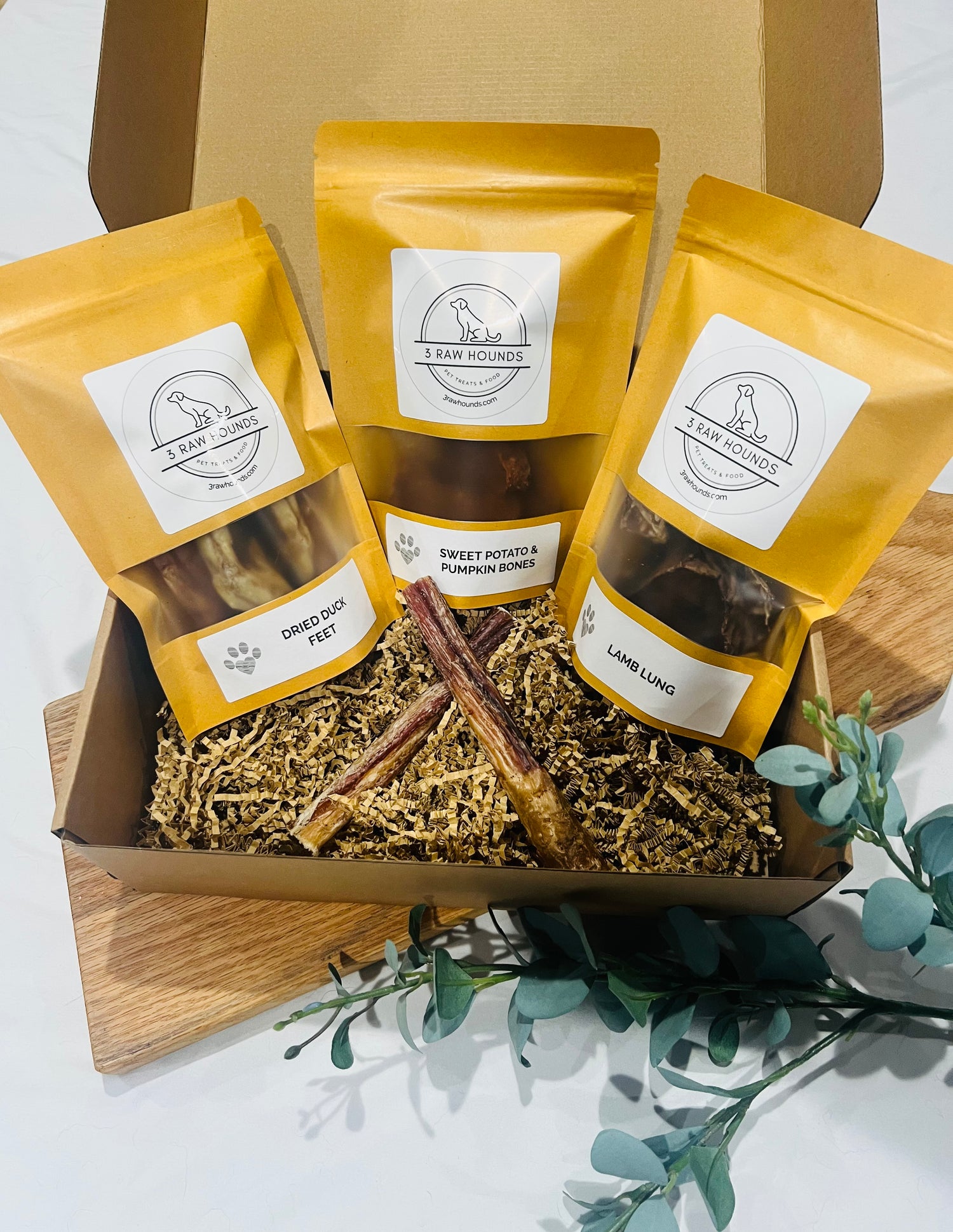 Small dog sniffing the Tiny Tails Box filled with natural, single-ingredient treats made for puppies and small breeds.