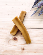 Two yak chews placed on a wooden surface with a sprig of lavender in the top right corner.